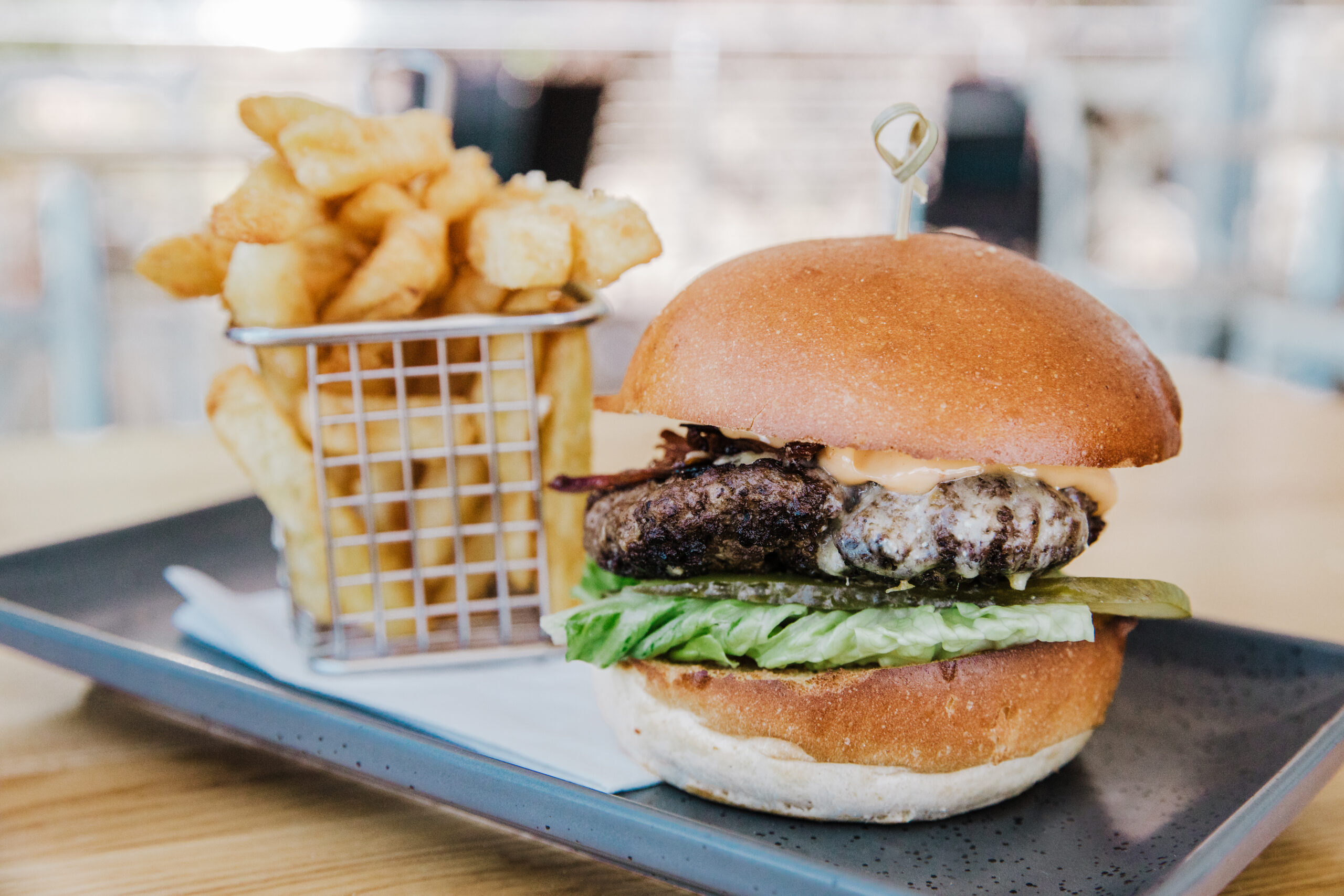 Sorrento Beef Burger on a plate with a basket of chips