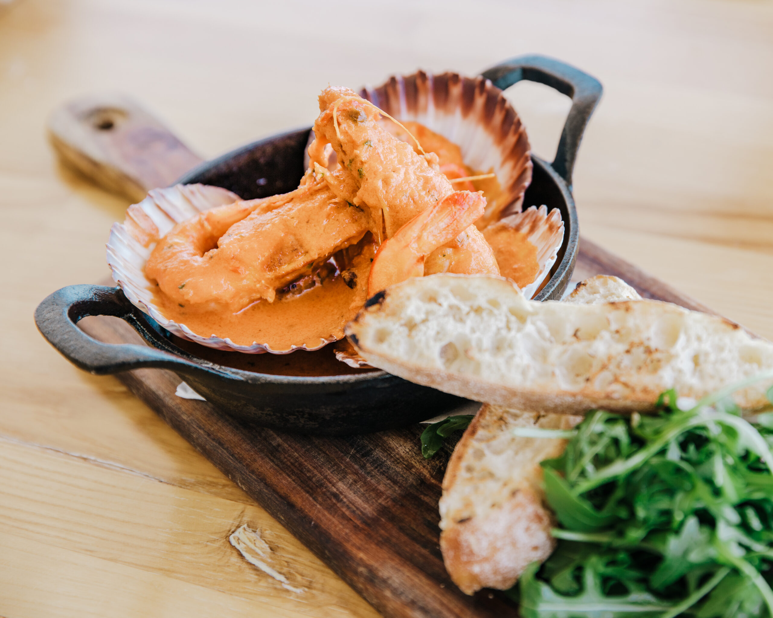 Prawn gambiri on serving platter wit bread and rocket