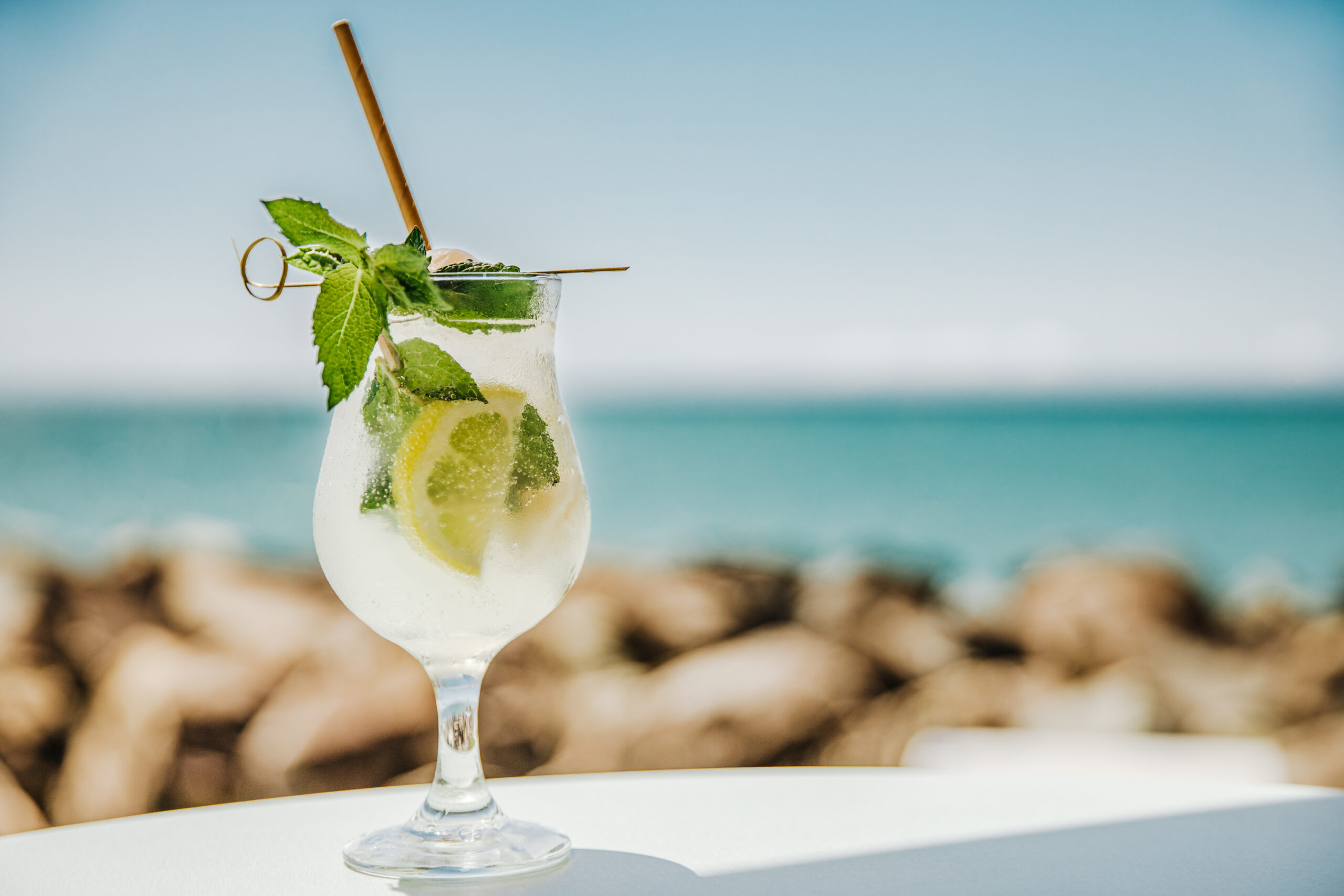 A mojito on a table overlooking the ocean